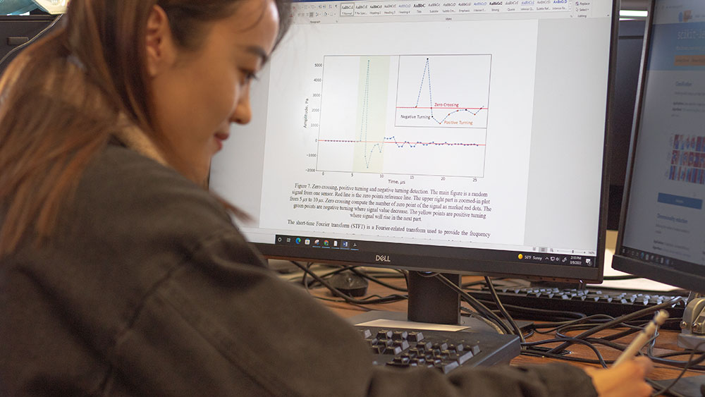 female petroleum engineering student at Texas A&amp;M University studying a graph of data analysis results on a computer monitor