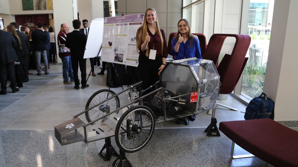 Two students display their prototype at the 2019 Engineering Project Showcase.